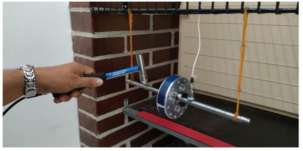 Experimental setup showing the suspended shaft, accelerometer, and impact hammer for simulating free-free boundary conditions